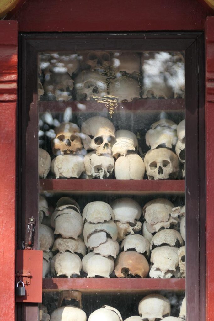 In einer verglasten Vitrine mit rotem Holzrahmen liegen gestapelte Schädel und Knochen - ein Relikt aus dem Khmer-Königreich.