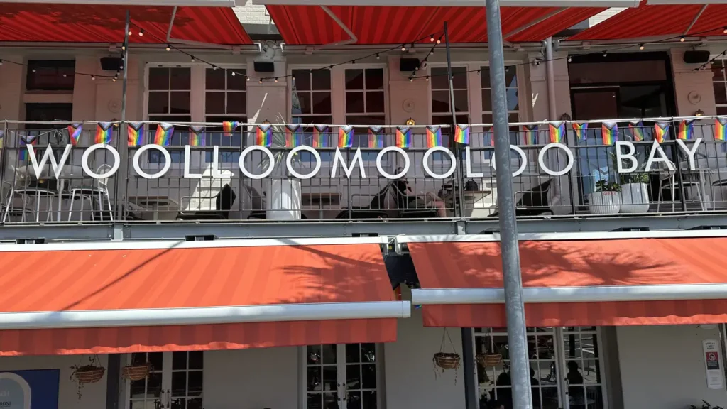 Das "Woolloomooloo Bay"-Gebäude mit Regenbogenfahnen am Balkon und rot-weiß gestreiften Markisen wirkt richtig einladend!.