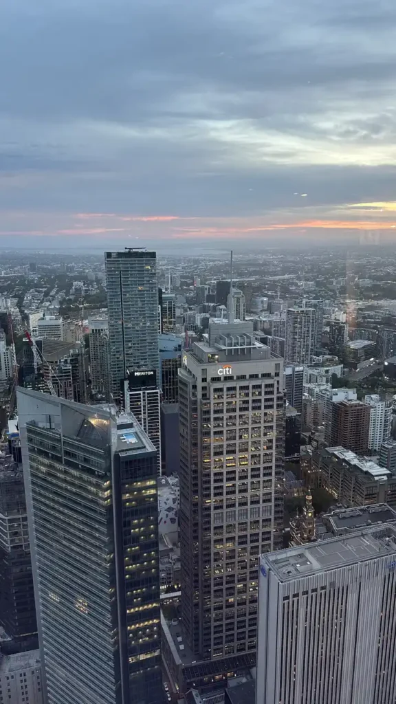 Die Skyline bei Sonnenuntergang zeigt erleuchtete Bürotürme wie Scotiabank und Citi unter bewölktem Himmel mit Abendlicht.
