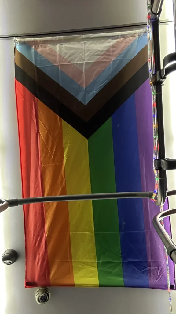 Die bunte Progress-Pride-Flagge hängt drinnen, teilweise von Metallstangen eingerahmt - ein schönes, vielfältiges Zeichen.