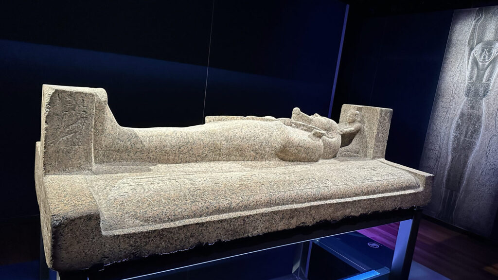 In einem sanft beleuchteten australischen Museum bestaunen wir einen steinernen Sarkophag mit altägyptischer Figur und Infotafeln.