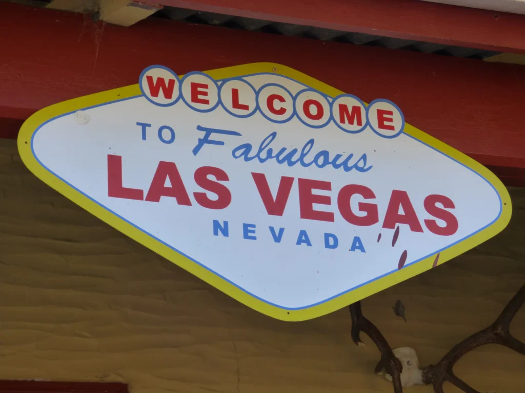 Ein Schild, das dem berühmten "Welcome to Fabulous Las Vegas, Nevada"-Schild ähnelt, mit roter, blauer und gelber Schrift auf weißem Hintergrund, montiert unter einem roten Dach - dieses markante Wahrzeichen befindet sich auf der Südinsel von Neuseeland.
